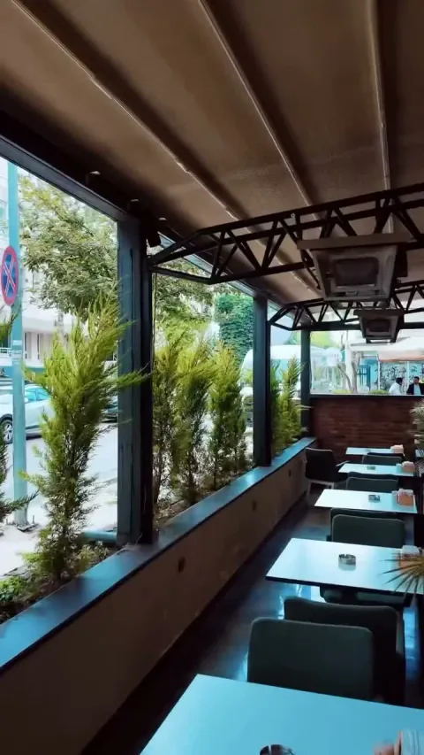 Lila Coffee’nin yeşilliklerle çevrili cam kenarı oturma alanı